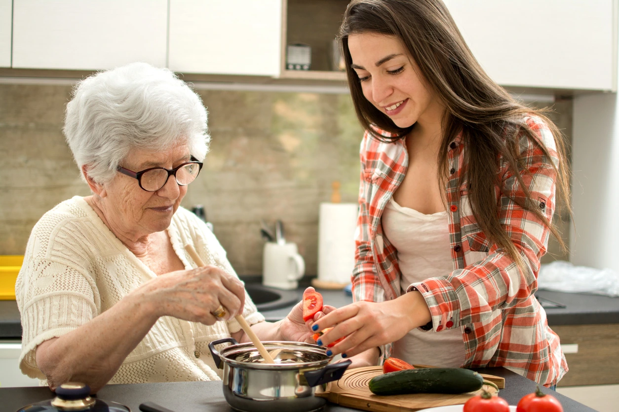 Inwonende hulp voor bejaarden helpt een oudere vrouw in de keuken met het bereiden van een maaltijd